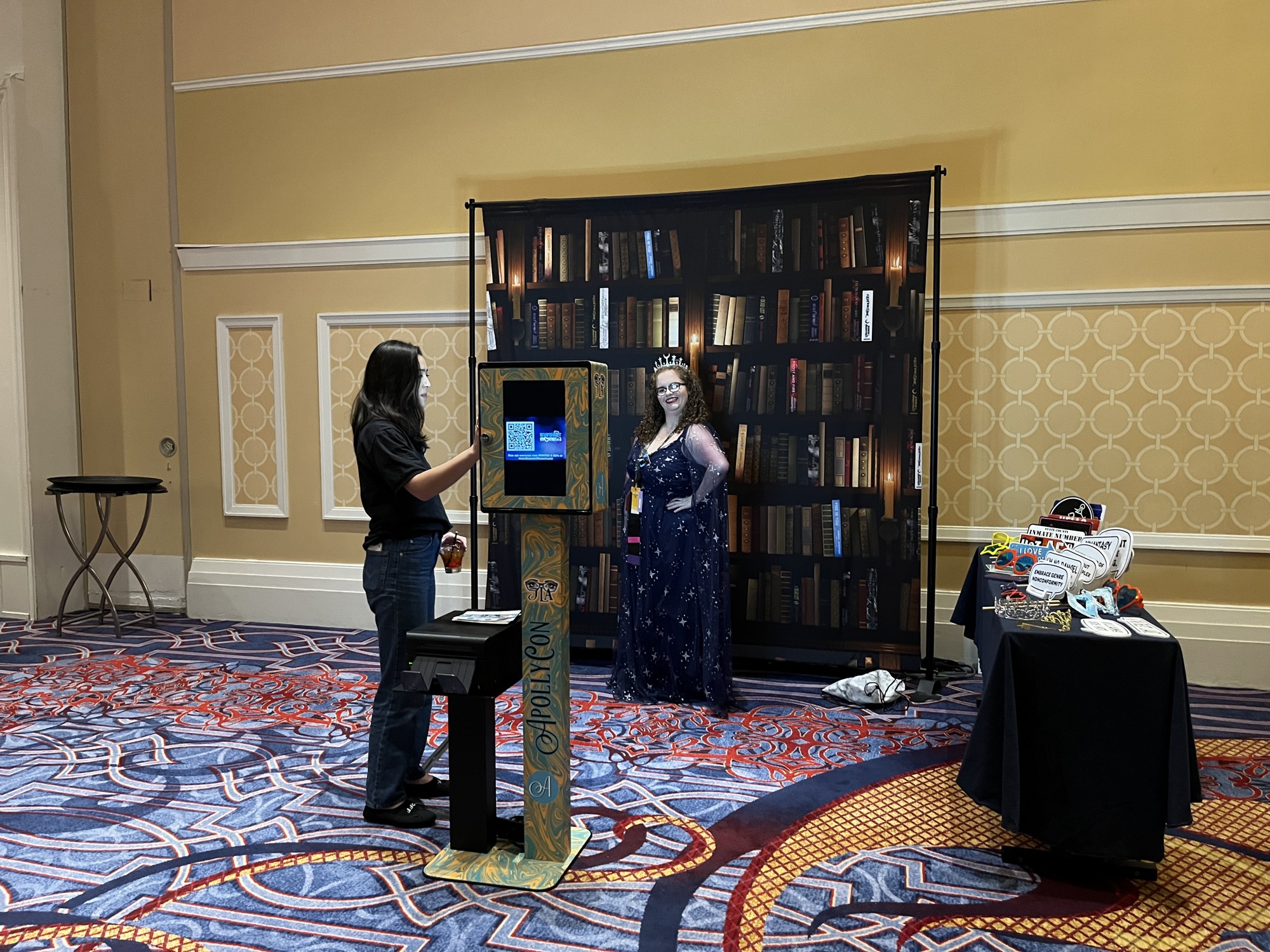 The branded self-service booth and printed bookshelf backdrop set up inside the convention venue