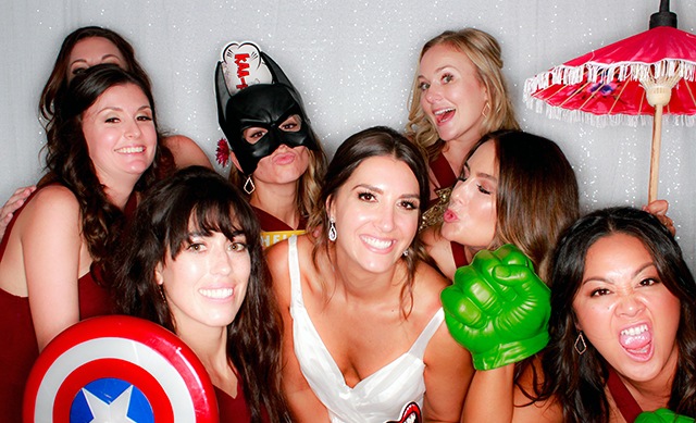 Bride and bridesmaids laughing with wedding photo booth props