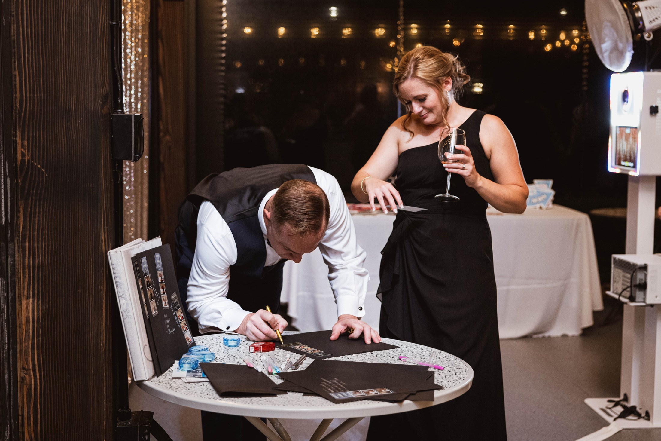 A wedding guest writing a note in the couple’s photo guestbook