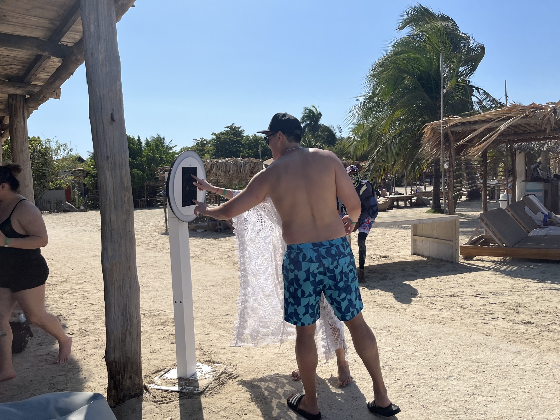 Guests using the selfie booth touchscreen at a beach celebration