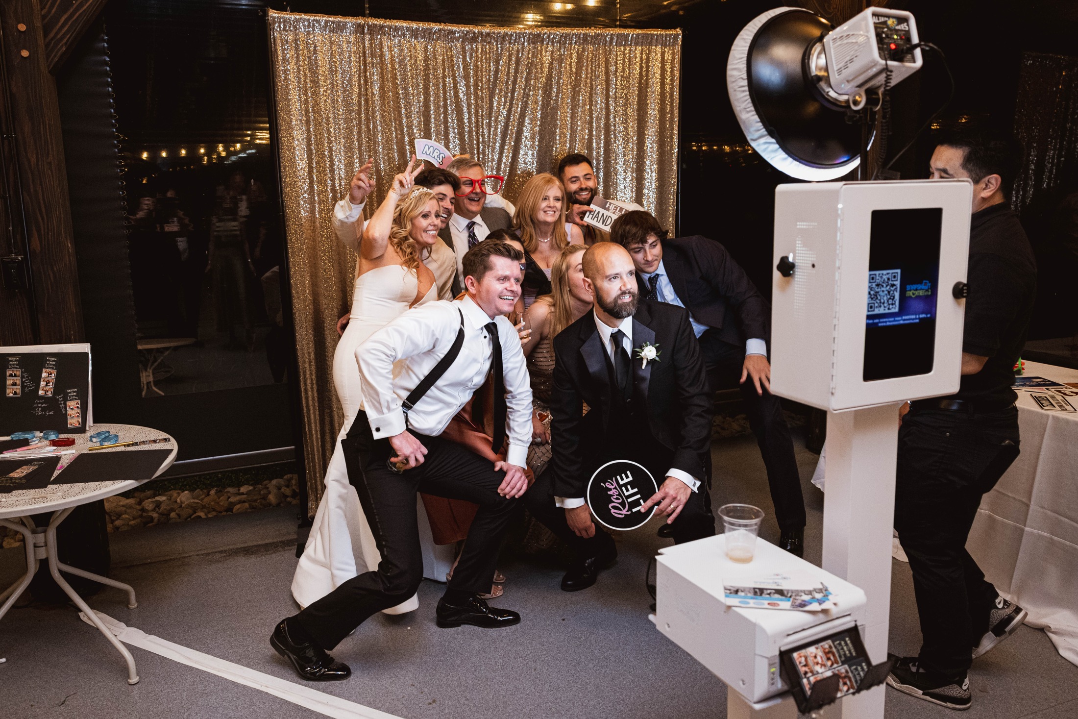 Real wedding guests posing together in front of an open-air photo booth